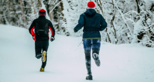 Two male athlete running on winter alley in Park