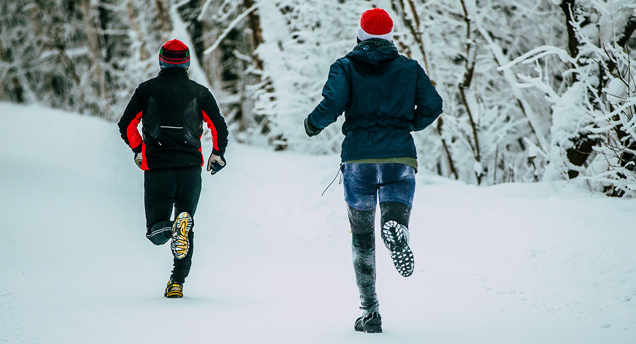 Two male athlete running on winter alley in Park